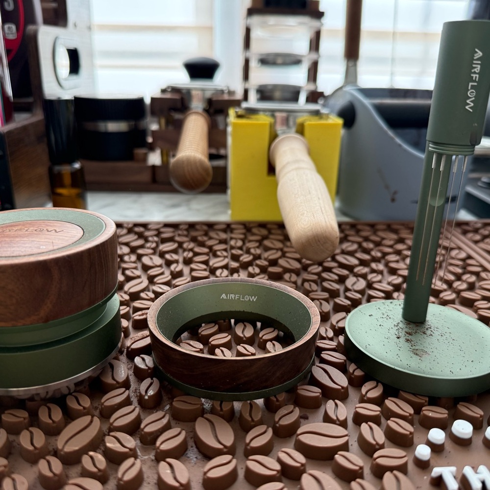 A set of airflow coffee distributor, dosing funnel, and WDT tool with a stand